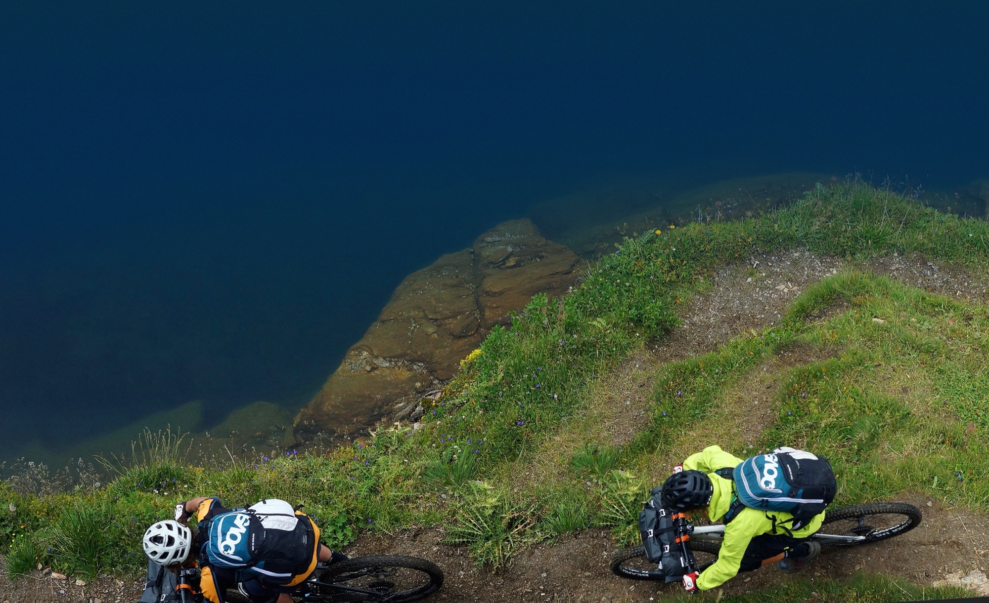 Due rider su un sentiero sopra un lago di montagna